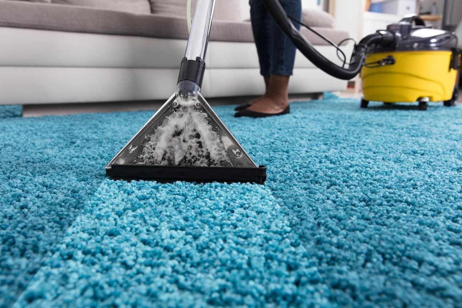 Cleaner in an apron vacuuming a living room floor