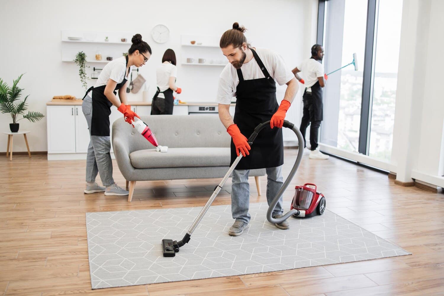 Team of cleaners vacuuming and wiping down a bright living room